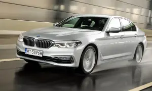 Srebrne BMW 520d xDrive pędzi po mokrej drodze w tunelu, rozpryskując wodę.