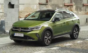 Zielony Volkswagen Taigo na brukowanej ulicy, z charakterystycznym dachem i felgami.