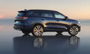 Granatowy Renault Espace 2024 z odbiciem na wodzie, na tle zachodzącego słońca.