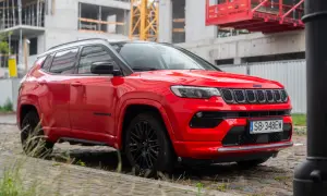 Czerwony Jeep Compass na tle budowy. Wiele osób szuka jeep compass opinie przed zakupem.