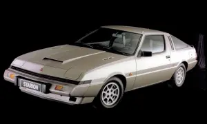 Klasyczny Mitsubishi Starion w kolorze szampańskim, z charakterystycznym wlotem powietrza na masce, prezentuje się na czarnym tle.