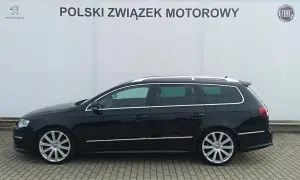 Czarny Volkswagen Passat kombi, model r36, zaparkowany przed budynkiem z logo Polskiego Związku Motorowego.
