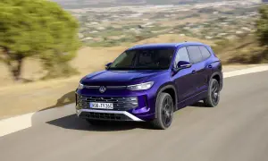 Fioletowy VW Tayron jedzie po krętej drodze wśród wzgórz.