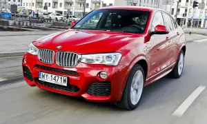 Czerwone BMW X4 2025 pędzi ulicą, błyszcząc w słońcu. Kierowca w środku, gotowy na przygodę.