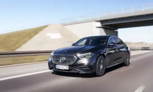Czarny Mercedes E220d pędzi autostradą pod mostem.