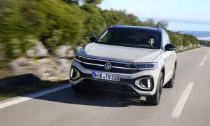 Jasnoszary Volkswagen T-Roc jedzie po krętej drodze. Nawet przy potencjalnych volkswagen t-roc usterki, auto prezentuje się dynamicznie.