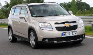 Złoty Chevrolet Orlando na drodze. Kierowca w środku, widok z przodu. Wiele osób szuka chevrolet orlando opinie przed zakupem.