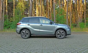 Szary Suzuki Vitara 2023 zaparkowany na tle sosnowego lasu.