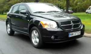 Czarny Dodge Caliber 1.8, jaki to silnik? Auto jedzie po mokrej drodze, w tle drzewa.