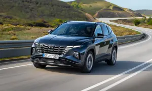 Ciemnoszary Hyundai Tucson na zakręcie drogi. Sprawdź jego imponujące hyundai tucson wymiary i ciesz się jazdą po malowniczej trasie.