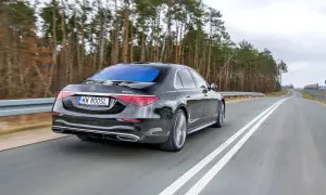 Czarny Mercedes S400d 4Matic z tablicą WW 800SL jedzie po drodze wśród drzew.