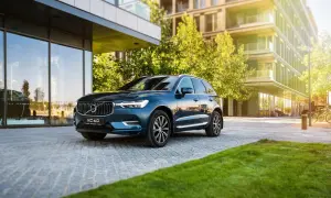Elegancki, ciemnoniebieski Volvo XC60 zaparkowany przed nowoczesnym budynkiem. Wiele osób szuka volvo xc60 opinie, by podjąć decyzję o zakupie.