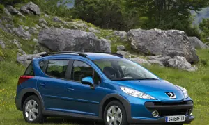 Niebieski Peugeot 207 SW na tle skalistego, zielonego krajobrazu. Idealny na wycieczkę poza miasto.