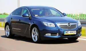 Niebieski Opel Insignia 1.6 Turbo pędzi po drodze. Kierowca wpatrzony w horyzont.