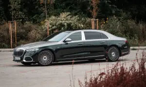 Elegancki Maybach S680 w ciemnozielonym kolorze z dwukolorowym nadwoziem, zaparkowany na tle jesiennej zieleni.