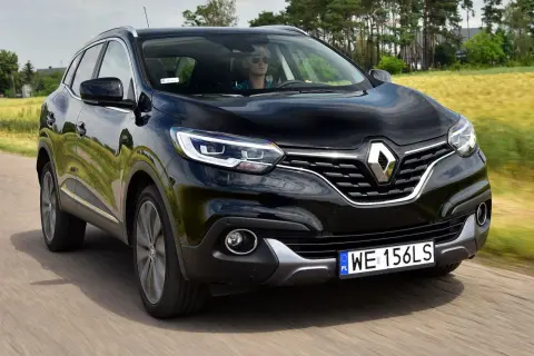 Czarny Renault Kadjar w ruchu. Kierowca w okularach przeciwsłonecznych. Wiele pozytywnych renault kadjar opinie potwierdza jego walory.