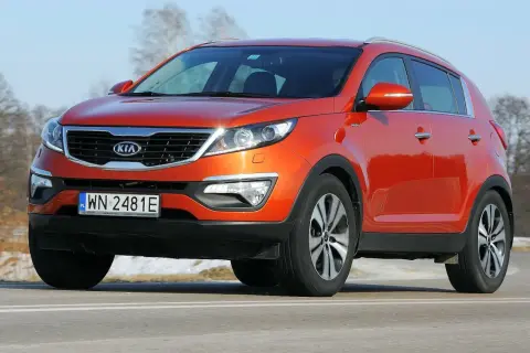 Pomarańczowy Kia Sportage 2012 na drodze, z widocznym numerem rejestracyjnym WN 2481E.