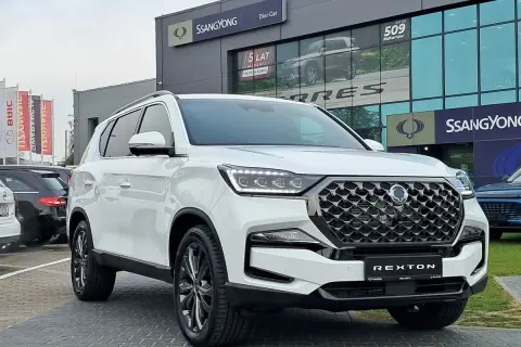 Biały SsangYong Rexton na tle salonu samochodowego. Elegancki SUV gotowy na przygodę.