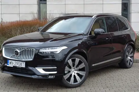 Elegancki, czarny Volvo XC90 z chromowanymi felgami stoi na brukowanym podjeździe.