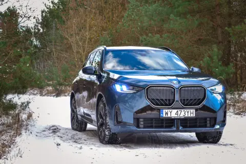 Nowy BMW X3 2024 w zimowej scenerii lasu, gotowy na każdą drogę.