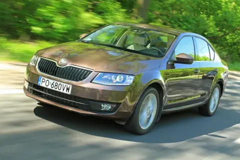 Brązowa Skoda Octavia jedzie po drodze wśród zieleni. Sprawdź aktualną skoda octavia cena!