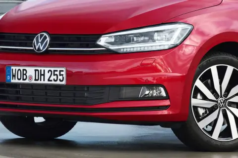 Czerwony Volkswagen Touran z błyszczącym logo i nowoczesnymi światłami.