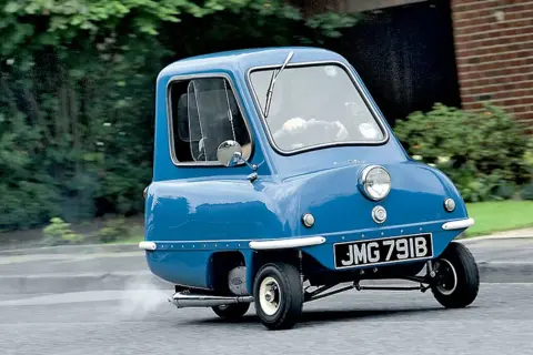 Niebieski Peel P50, najmniejszy samochód świata, w ruchu. Zastanawiasz się nad peel p50 cena?