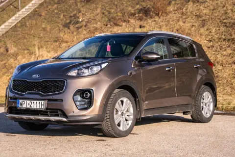 Brązowy Kia Sportage 2018 gotowy na przygodę. Elegancki SUV na tle słonecznego, suchego krajobrazu.