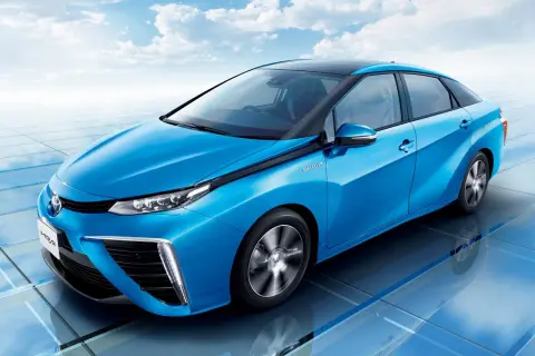 Niebieski samochód Toyota Mirai na tle błękitnego nieba z chmurami.