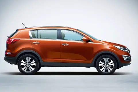 Pomarańczowy Kia Sportage 2013 z profilu, z błyszczącymi felgami i chromowanymi klamkami, gotowy na przygodę.