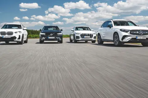 Białe i czarne SUV-y, w tym modele Mercedes, jadące po drodze.