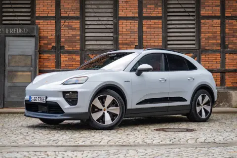 Biały Porsche Macan Electric na bruku przed ceglanym budynkiem. Sprawdź aktualną porsche macan cena.