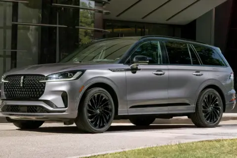 Szary Lincoln Aviator z czarnymi felgami stoi przed nowoczesnym budynkiem.