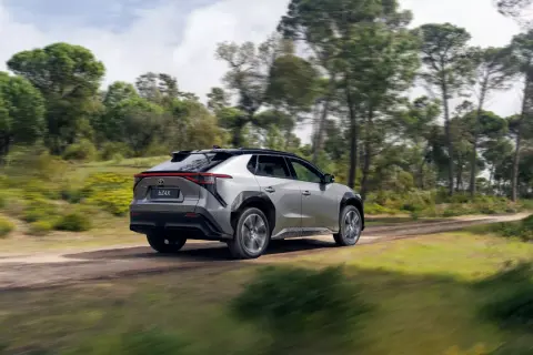 Srebrny Toyota bz4x cena jest atrakcyjna, gdy jedzie po leśnej drodze.
