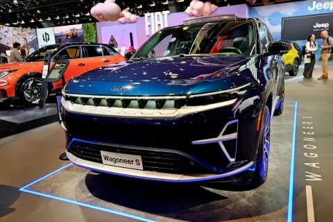 Nowy, lśniący, granatowy Wagoneer S z niebieskim podświetleniem na wystawie motoryzacyjnej.