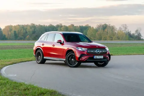 Czerwony Mercedes-Benz GLC 300 na zakręcie toru wyścigowego, z jesiennym lasem w tle.