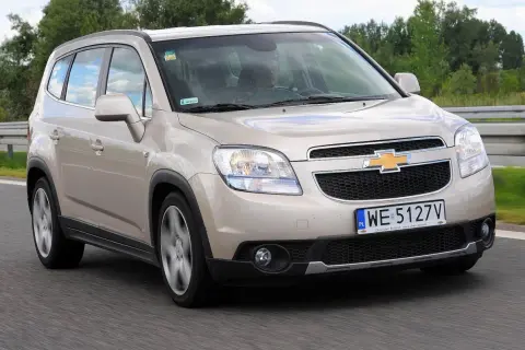 Złoty Chevrolet Orlando na drodze. Kierowca w środku, widok z przodu. Wiele osób szuka chevrolet orlando opinie przed zakupem.
