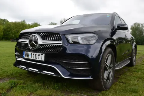 Ciemnoniebieski Mercedes GLE 450 stoi na trawie, z przodem skierowanym w stronę widza.