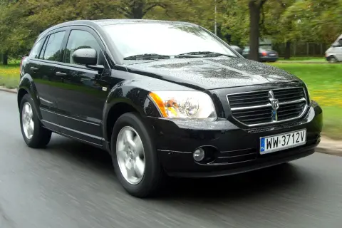 Czarny Dodge Caliber 1.8, jaki to silnik? Auto jedzie po mokrej drodze, w tle drzewa.