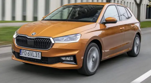 Pomarańczowa Skoda Fabia 2021 pędzi po drodze, jej reflektory ostro świecą, a felgi wirują w ruchu.