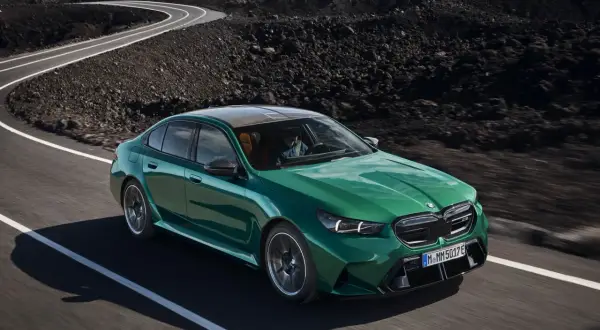 Zielony BMW M5 2025 pędzi po krętej drodze wśród wulkanicznych krajobrazów.