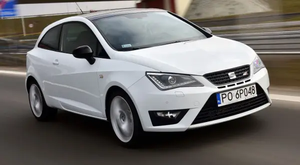 Biały Seat Ibiza 1.4 benzyna w ruchu, z czarnym dachem, na drodze.