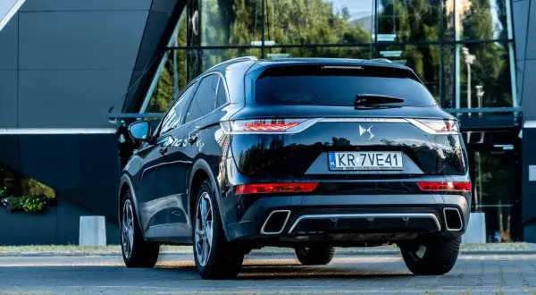 Elegancki czarny Citroën DS7 Crossback z polskimi tablicami rejestracyjnymi stoi przed nowoczesnym budynkiem.