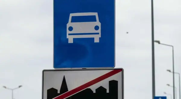 Znak drogowy ekspresowy z symbolem samochodu i znak końca drogi ekspresowej z sylwetką miasta.