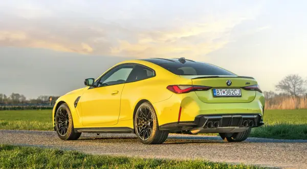 Żółte BMW M4 Competition na tle zachodzącego słońca. Sprawdź aktualną bmw m4 competition cena.