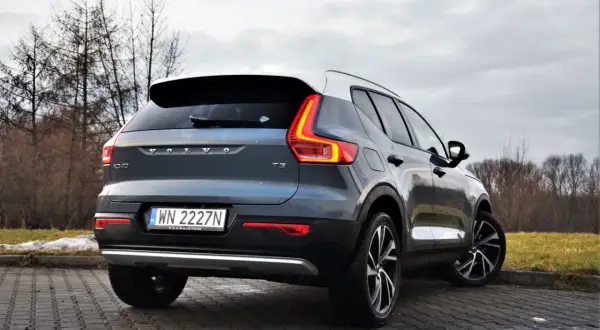 Tylny widok na ciemnoszary Volvo XC40 T3 z białym dachem, zaparkowany na brukowanej nawierzchni.