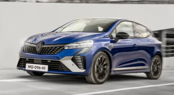 Niebieski Renault Clio 2024 pędzi po drodze, jego nowoczesny design i dynamiczna sylwetka przyciągają wzrok.