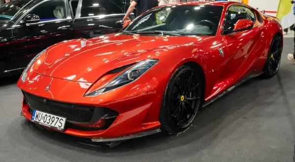 Błyszczący, czerwony Ferrari 812 Superfast z czarnymi felgami na wystawie motoryzacyjnej.