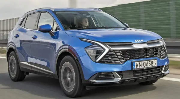 Nowa Kia Sportage w kolorze niebieskim jedzie po drodze.