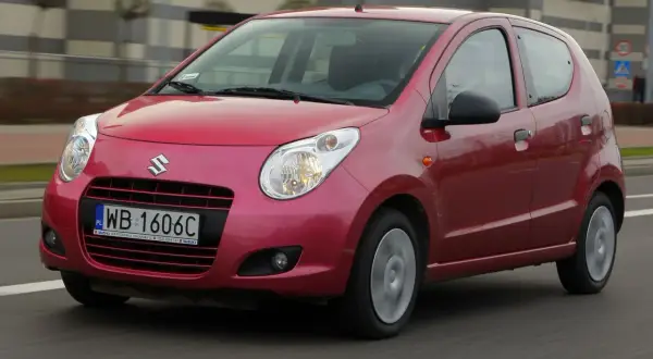 Czerwony Suzuki Alto z polskimi tablicami rejestracyjnymi WB 1606C jedzie po drodze.
